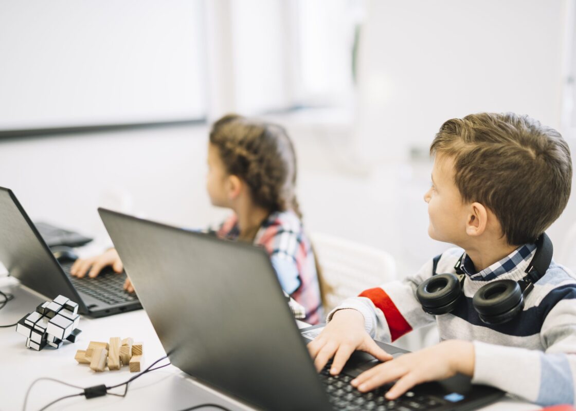 school-children-sitting-with-laptop-looking-blackboard-scaled-1